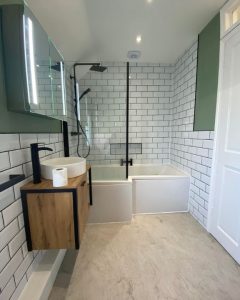 A new bathroom installation featuring white tiled walls, a shower over bath and floating sink.