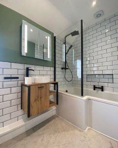 A new bathroom installation featuring white tiled walls, a shower over bath and floating sink.