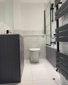 A new bathroom installation featuring a hanging radiator, new bathroom cabinet and WC.