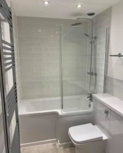 A new bathroom installation featuring tiled walls, a new toilet and a shower over bath.