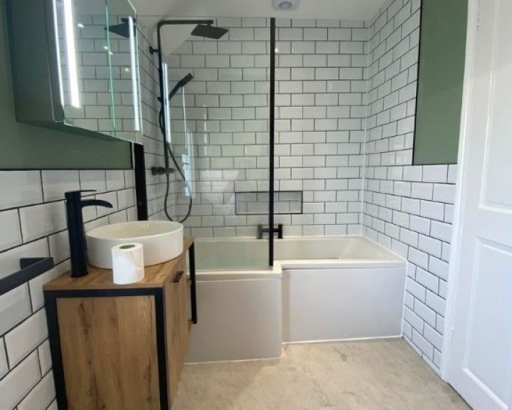 A new bathroom installation featuring white tiled walls, a shower over bath and floating sink.