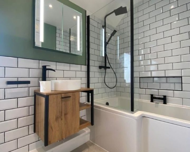 A new bathroom installation featuring white tiled walls, a shower over bath and floating sink.