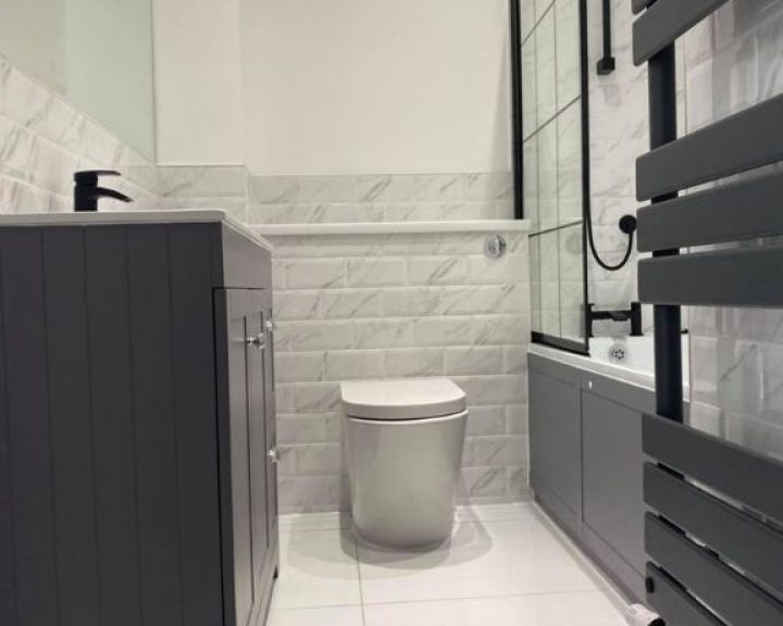 A new bathroom installation featuring a hanging radiator, new bathroom cabinet and WC.