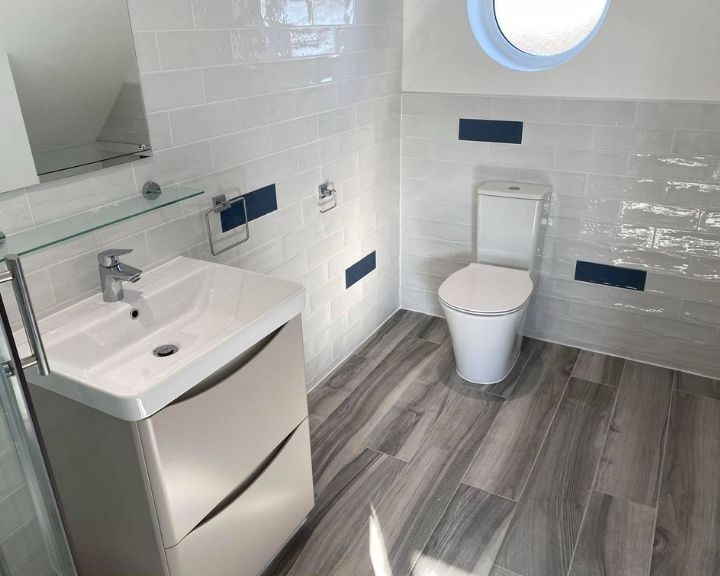 A new bathroom design featuring vinyl flooring, blue and white wall tiling, a sink and toilet.