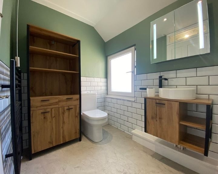 A new bathroom installation featuring white tiled walls, a new toilet and a floating sink with cabinets underneath.