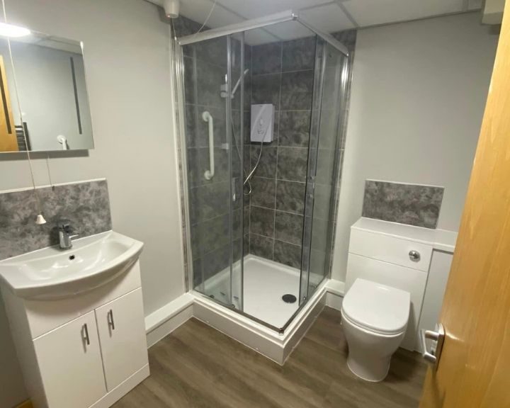 A new bathroom installation in Basingstoke featuring a shower and enclosure, tiled walls and a new sink and WC.