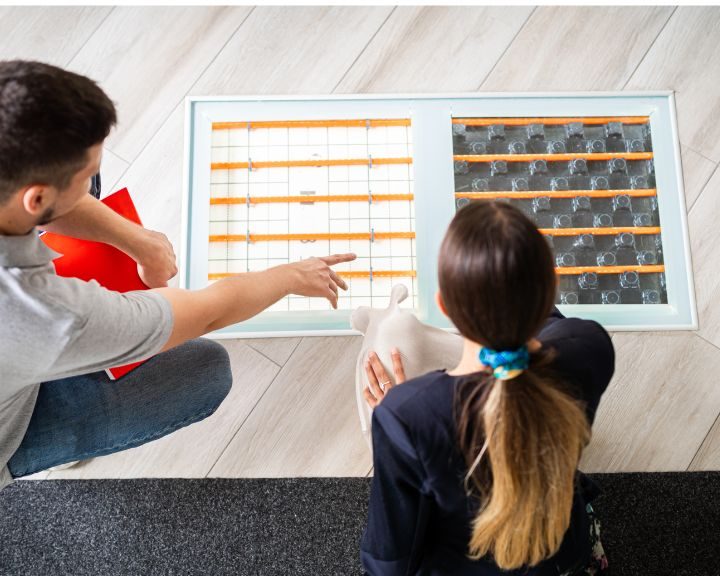 An underfloor heating contractor showing a customer the difference between hydronic and electric underfloor heating.